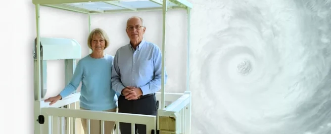 Elderly couple stands on home elevator platform, smiling against a swirling hurricane backdrop.