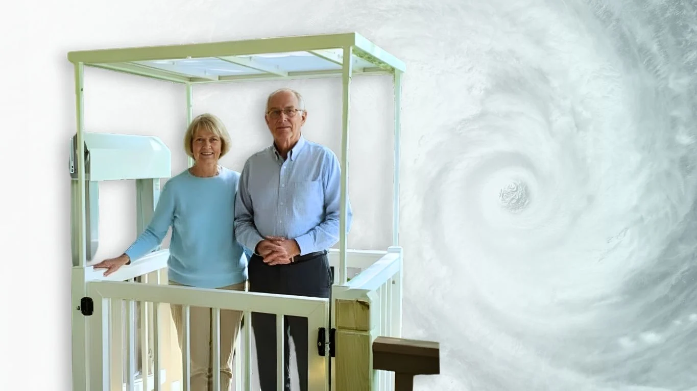 Elderly couple stands on home elevator platform, smiling against a swirling hurricane backdrop.
