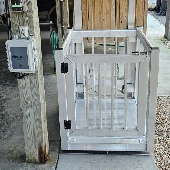 Outdoor platform lift with metal railings, adjacent to control box and wood structure, suitable for use as home elevators.